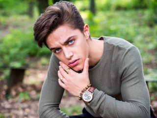 One handsome blue eyed young man in urban setting in European city park