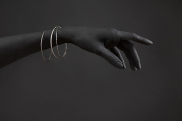 Black woman's hand with Silver jewelry. Oriental Bracelets on a black painted hand. Silver Jewelry