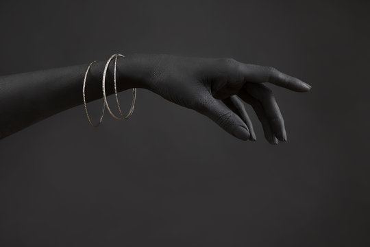 Black woman's hand with Silver jewelry. Oriental Bracelets on a black painted hand. Silver Jewelry