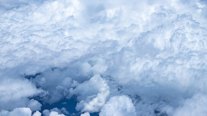 Beautiful view from window of plane flying over clouds. Natural panorama with clouds. White clouds moving above the ground. 