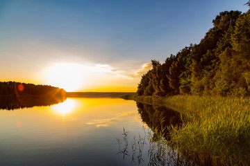 ein See umgeben von Wald bei Sonnenuntergang