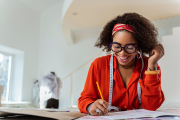 Smiling good-looking young designer constructing future costumes
