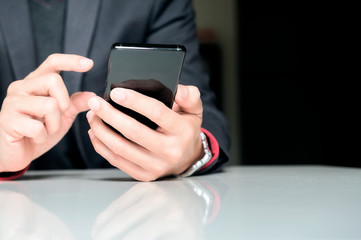 Close up of a business man using mobile smart phone while sitting at office