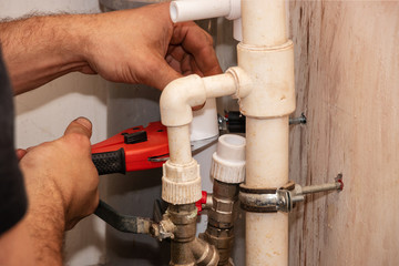 Cutting plastic pipe. Plumber holds in his hand a pipe cutter for polypropylene pipes