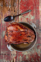 Spiral-cut baked glazed ham on rustic painted table flat lay