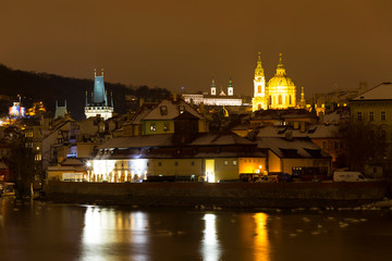 Obraz premium Night romantic snowy Prague St. Nicholas' Cathedral above River Vltava, Czech republic