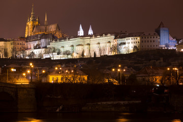 Night snowy Christmas Prague Lesser Town with gothic Castle above River Vltava, Czech republic
