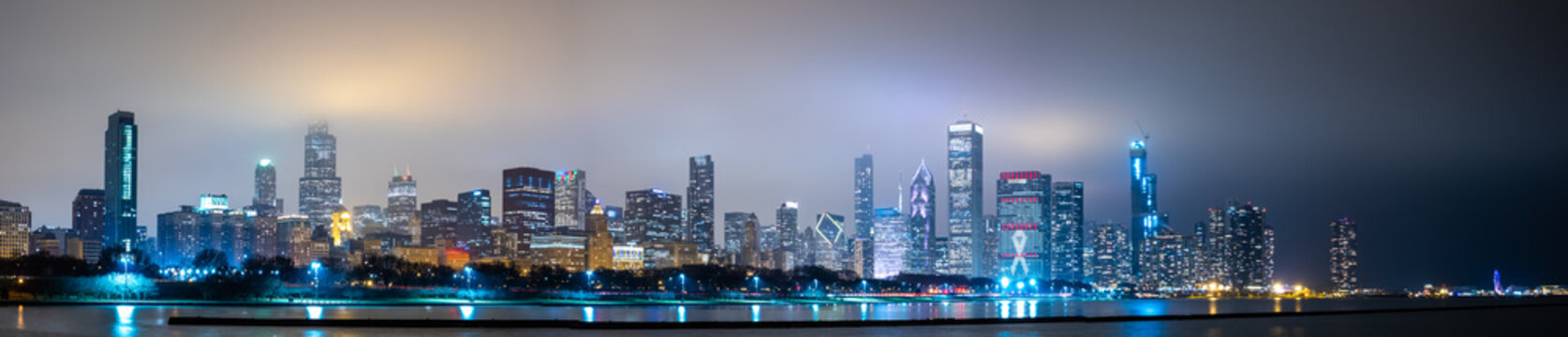 Long Panoramic View Of Chicago Skyline At Night With Top Of The Buildings Covered In Fog