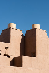 Two stucco chimneys with a clear blue sky in the background.