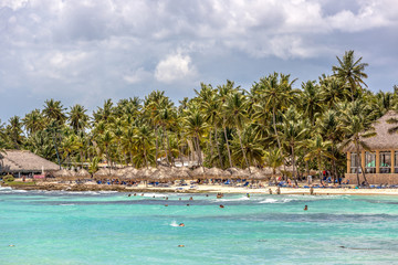 Bayahibe, Dominican Republic - July 22nd 2018 - Tourists having fun in the blue water of the Bayahibe beach with palm trees in Dominican Republic