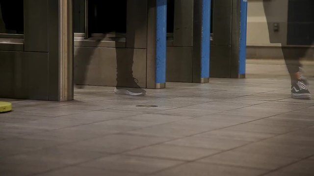 A close-up of commuters feet walking through an entry gate in a Canada Line station in Vancouver, BC, with a crossfade effect.