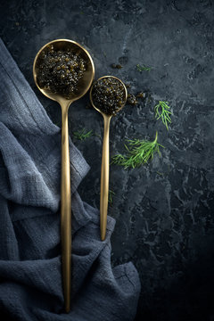Black caviar in spoons on dark background. Natural sturgeon black caviar closeup. Delicatessen. Top view, flatlay