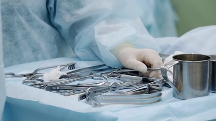 experienced medical nurse is preparing tools for surgery operation, putting them on table