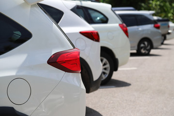 Closeup of rear side of white cars park in parking area in sunny day. 