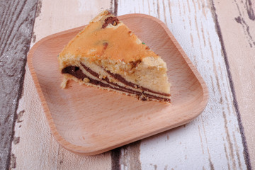 Slice of homemade marble cake on a wooden plate with vintage wooden table background