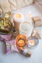 Stylish still life with gift boxes, candle sticks, burning candles, garland on light windowsill background, boho romance concept background and style