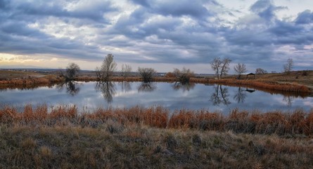 Views of Josh’s Pond walking path, Reflecting Sunset in Broomfield Colorado surrounded by Cattails, plains and Rocky mountain landscape during sunset. United States.