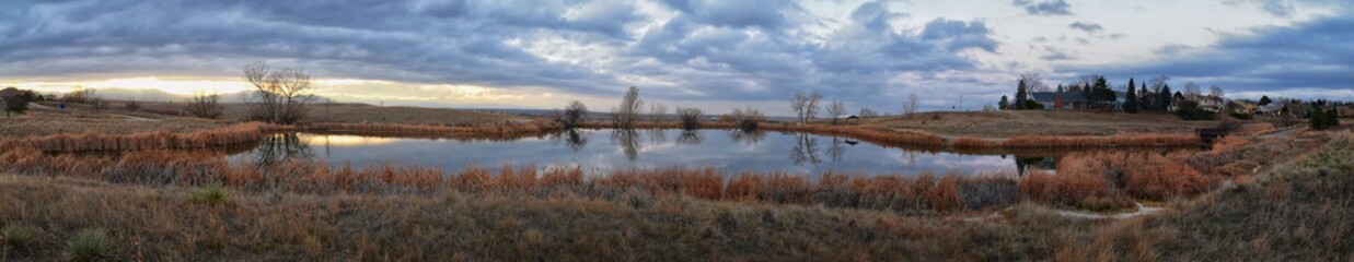 Views of Josh&rsquo;s Pond walking path, Reflecting Sunset in Broomfield Colorado surrounded by Cattails, plains and Rocky mountain landscape during sunset. United States.