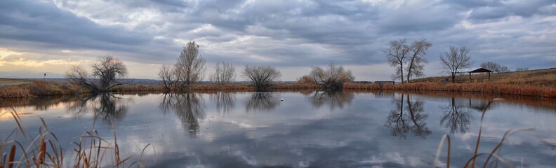Views of Josh’s Pond walking path, Reflecting Sunset in Broomfield Colorado surrounded by Cattails, plains and Rocky mountain landscape during sunset. United States.