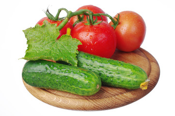 Tomatoes and cucumbers on the kitchen board. Close-up. Isolated on white 