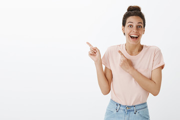 Good-looking enthusiastic and surprised happy young woman with tan and hairbun smiling broadly with...