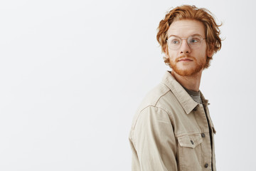 Studio shot of dreamy handsome young redhead guy passing by interesting store and turning left with...