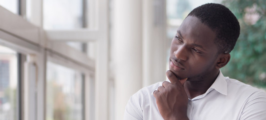 serious african business man thinking or planning; portrait of thoughtful black man thinking, planning, considering, finding a good idea; young adult african man model