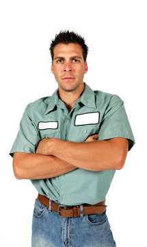 An adult male serviceman employee worker with blank name tag on shirt has arms folded and a serious look on his face.