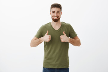 Man likes and supports your great idea. Portrait of cheerful and supportive charming bearded male in t-shirt showing thumbs up and smiling delighted, approving awesome dress on girlfriend