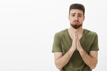 Please I beg you. Portrait of cute charming bearded male in need holding hands in pray,...