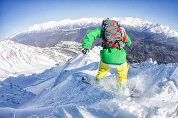 Freerider snowboarder jumping from a slope down in the mountains of the Caucasus, Krasnaya Polyana,...