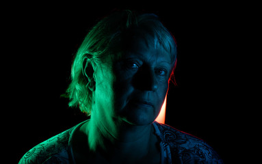 Portrait of a woman with colored light and dark background.