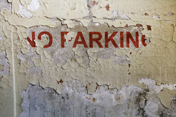 Old concrete wall with partially painted NO PARKING inscription