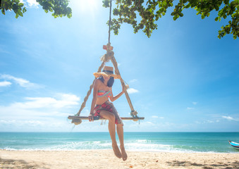woman enjoy happy the nature of the sea beach by sitting on the wooden swing tie under the shadow...