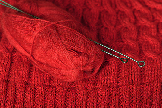 Knit. Knitted pattern and a skein of wool yarn with knitting on it. Red color