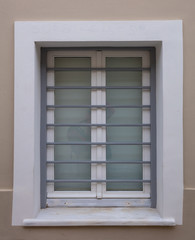 White wooden window with metal bars on beige color wall background, old town Plaka, Athens Greece