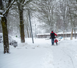 Man pushing his bicycle in snow