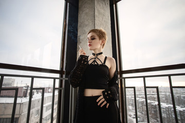 Girl with short hair stays on balcony and smokes