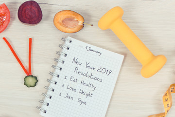 New year resolutions for 2019 and clock made of fresh fruits with vegetables, dumbbell and centimeter