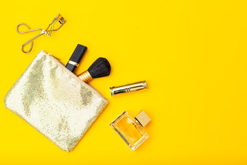 Handbag and feminine accessories gold color on yellow background. Copy space