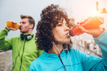 Sporty runners couple drinking energy drink  - obrazy, fototapety, plakaty