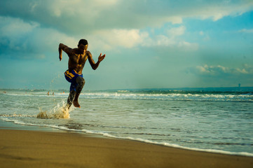 young attractive fit athletic and strong black African American man running at the beach training...