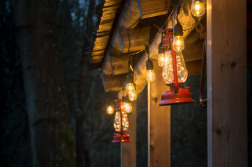 Red metal storm lantern hung outside rustic log cabin.