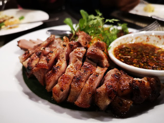 tasty slice grilled pork on white dish in Thai restaurant