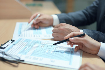Man filling in U.S. Individual income tax return, tax 1040 at table.
