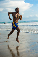 Fototapeta na wymiar young attractive fit athletic and strong black afro American man running at the beach training hard and sprinting on sea water in professional athlete lifestyle runner workout