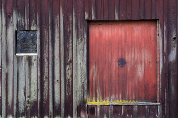 Abandoned Barn with red wooden door with small window by its side in Oregon