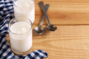 Two glasses of yogurt on a wooden table in the morning is healthy food. Yogurt made from milk fermented by added bacteria, often sweetened and flavored.