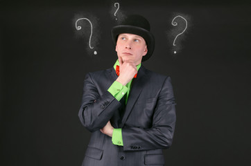 Pensive man in a bowler hat is thinking on a black background.