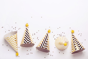 Striped golden cones hats and confetti on white background. Birthday holiday party concept